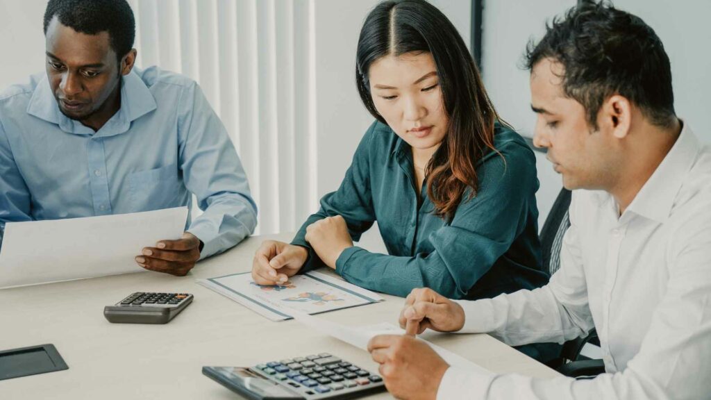 Three people working on financial documents.