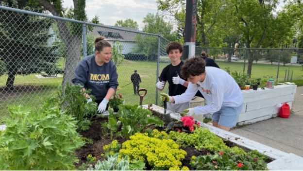 3 people planting a planter box.