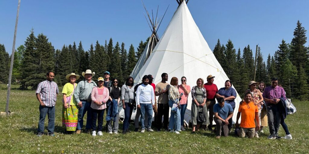 A group of diverse individuals posing in front of a Tipi as part of their ClimateReadyYYC grant project